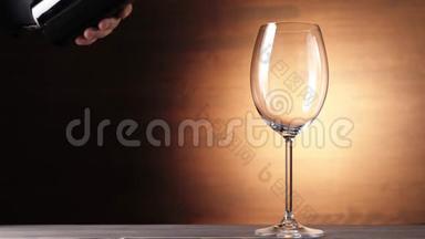 豪华红酒。在棕色背景下，用手从酒瓶里倒出美味的葡萄酒。玫瑰酒